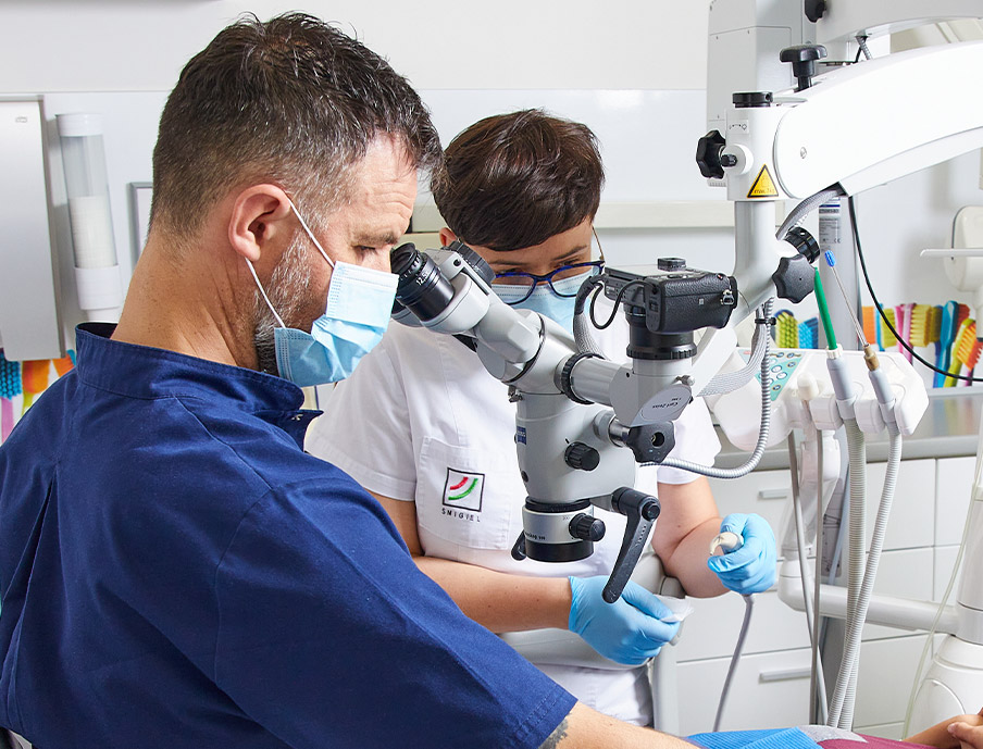 Stomatolog Kliniki implantologicznej Katowice bada pacjenta pod mikroskopem.