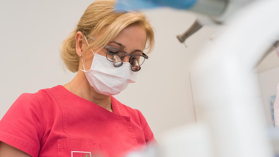Kobieta z urazami zębów w masce w gabinecie dentystycznym.