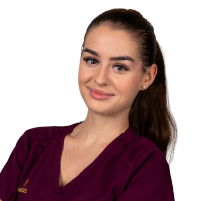 Natalia Przystalska, kobieta z długimi brązowymi włosami spiętymi w kucyk, ubrana w bordową bluzkę, stoi na białym tle i patrzy w kamerę z lekkim uśmiechem.