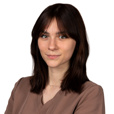 Katarzyna Sędłak, z prostymi ciemnobrązowymi włosami i grzywką, ubrana w ciemnoszarą bluzkę, pozuje na białym tle.